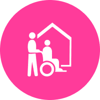 White icon of a standing person assisting a person in a wheelchair in front of a house, on a pink circular background.